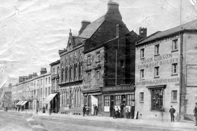 Dock Street in Fleetwood in the late 19th or early 20th century. Prominent buildings include John Gibson Ship and Boat Builder (on the right) and next door is J Smyth Auctioneer and Valuer. The old Fielden Library is also pictured in the centre
