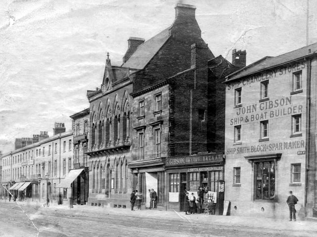 Dock Street in Fleetwood in the late 19th or early 20th century. Prominent buildings include John Gibson Ship and Boat Builder (on the right) and next door is J Smyth Auctioneer and Valuer. The old Fielden Library is also pictured in the centre