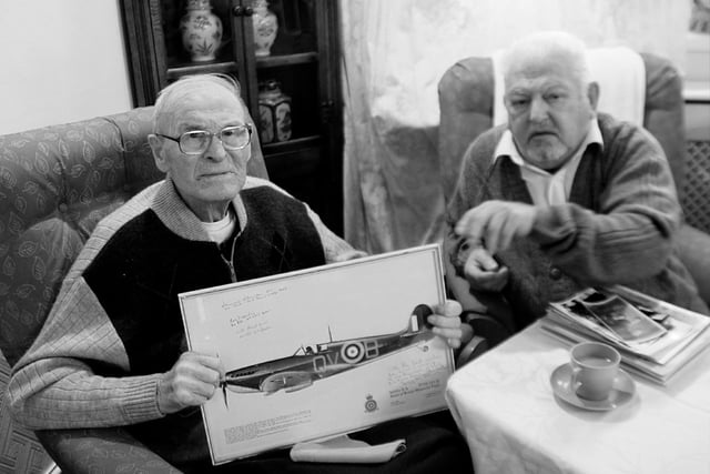 Captain Jan Martens holding a photo of the Spitfire he flew at the start of World War II. In later years, he flew bombers as part of his military service.