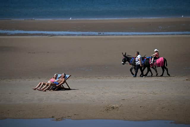 People sunbathe sit in deckchairs to sunbathe on the beach, as visitors take a donkey ride across the sand, in the sunshine in Blackpool, north west England on June 14, 2023 (Photo by Oli SCARFF / AFP) (Photo by OLI SCARFF/AFP via Getty Images)