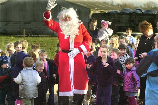 Father Christmas is greeted by children, after arriving by helicopter, at Singleton CE primary School Christmas Fair, 2002