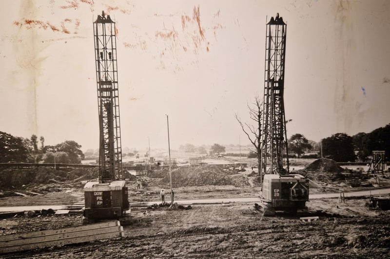 The caption for this picture from 1973 says: Two pile drivers stand where the M55 will join the M6 at Broughton. The camera looks out across the Fylde along the route the new road will take