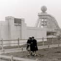 Two young girls stroll across a swathe of undeveloped land at the Pleasure Beach against the backdrop of the Big Dipper. The roller coaster was built by William Strickler at a cost of just £25,000