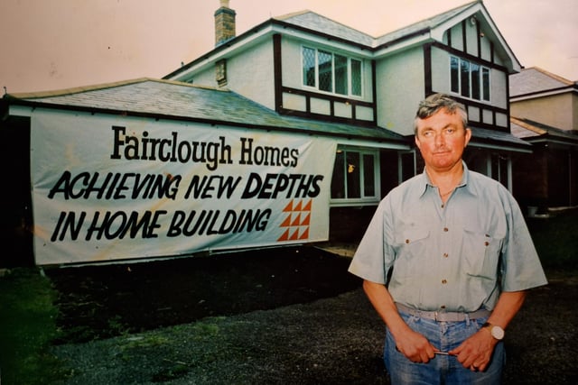 Clive Welch outside the luxury home which he never lived in. He had a cheeky sign made which he draped across the front of the collapsing house