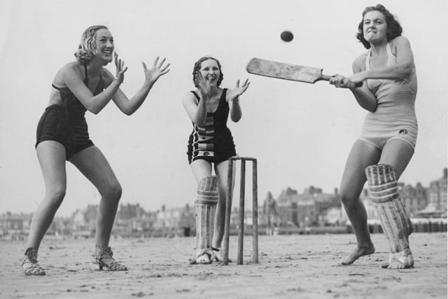 Three girls enjoying a game of cricket on the beach in 1937