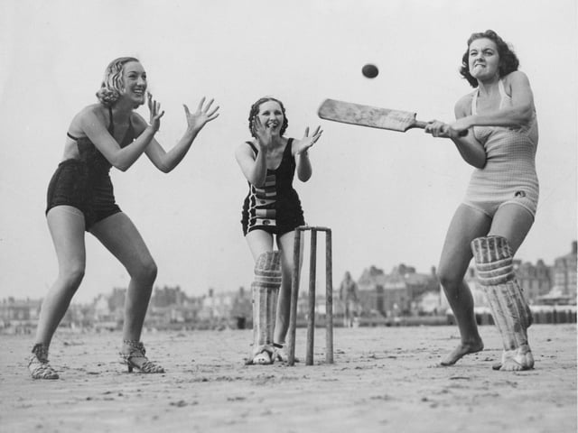 Three girls enjoying a game of cricket on the beach in 1937