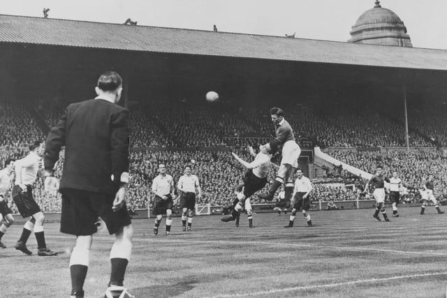 Referee Jack Barrick looks on as Jack Rowley, forward for Manchester United Football Club, jumps above Blackpool Football Club defender Eric Hayward to head the football towards goal to score during the FA Cup Final match on 24th April 1948 at Wembley Stadium. Manchester United won the game 4-1