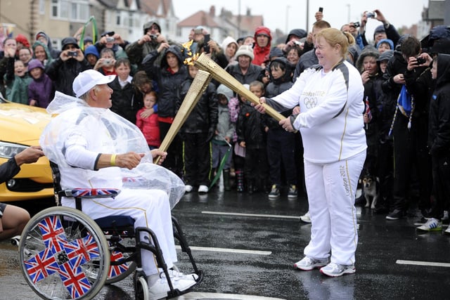 David Burns passes the Olympic Flame to Janette Mills on the Torch Relay leg between Fleetwood and Blackpool
