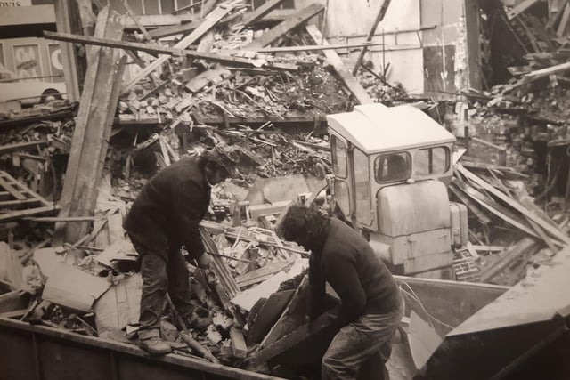 Workmen, sift through the rubble to dispose of it as the building comes down
