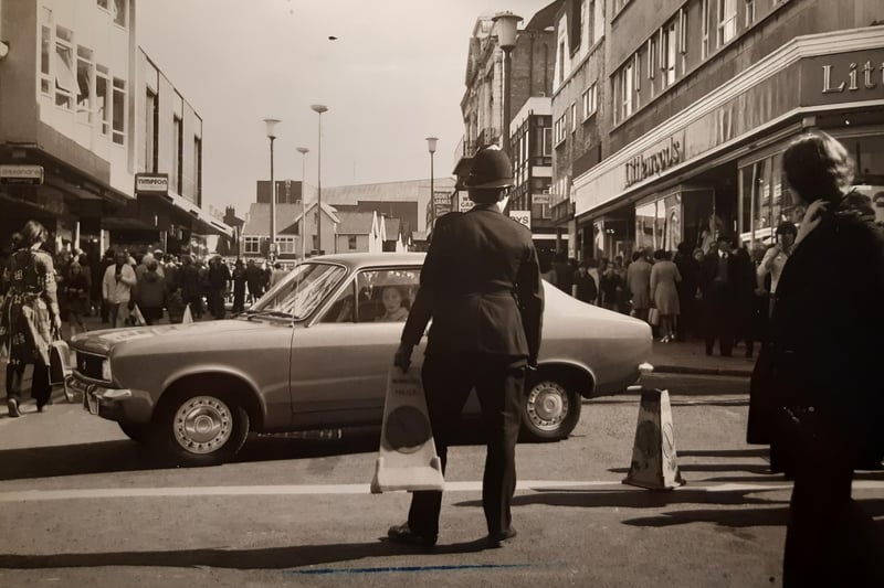 Littlewoods, Timpsons and a sign for Alexandra Clothing are pictured in this photo. The police officer looks like he was moving traffic cones. At the time road works were going on in Church Street