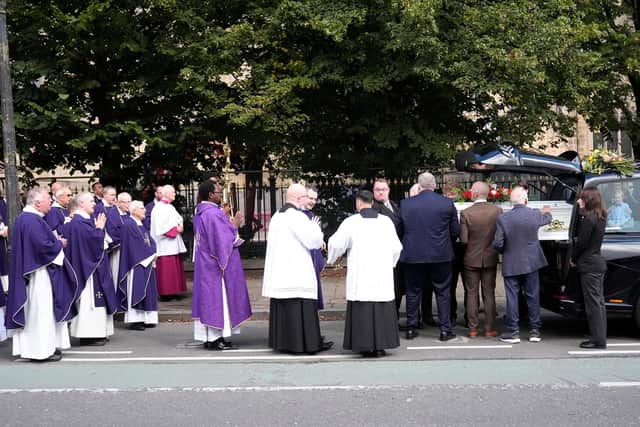 The coffin of Jimmy Cricket is carried by pallbearers to a hearse.