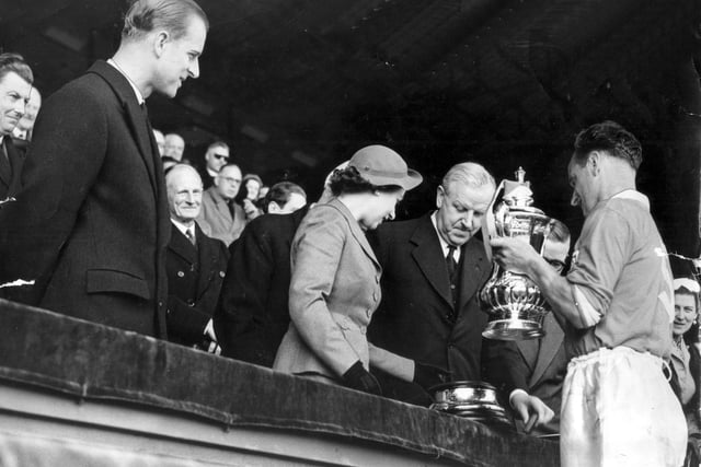 A young Queen Elizabeth and the Duke of Edinburgh present the trophy to a proud Blackpool FC team after they beat Bolton in the FA Cup Final, 1953