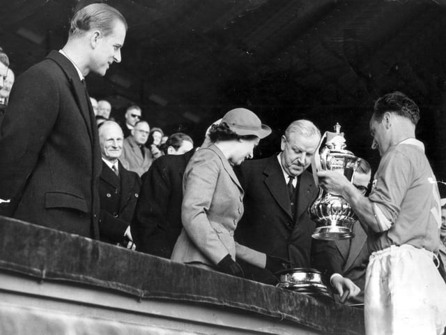A young Queen Elizabeth and the Duke of Edinburgh present the trophy to a proud Blackpool FC team after they beat Bolton in the FA Cup Final, 1953