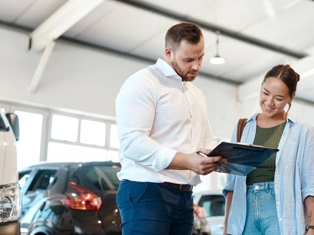 A car buyer discusses finance options with a dealership representative. New research suggests many UK drivers now regret the car finance deals they agreed to in the past decade.