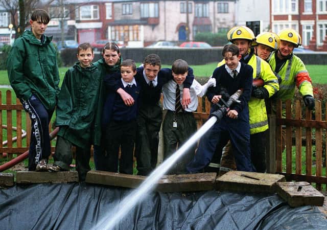 Filling of a new pond at Palatine High School, 1998. Eleven-year old Juan Montero mans the hose, helped by a team from South Shore Fire Station and fellow pupils