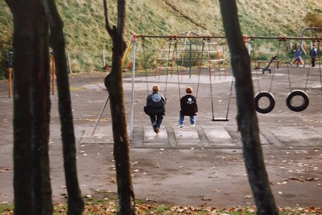 Two youngsters on the swings at Watson Road playground in 1994 under the rumble of Yeadon Way