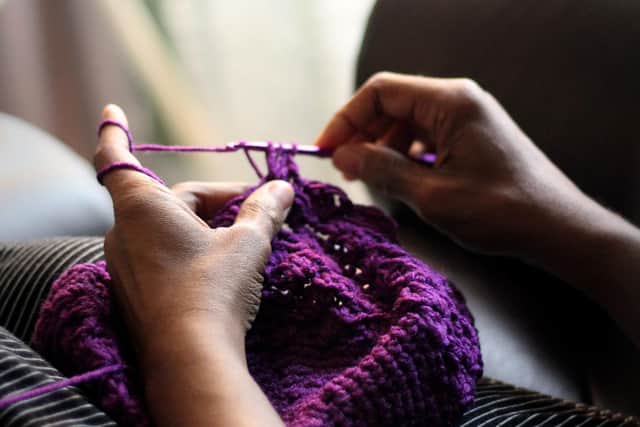 Photo of someone knitting with purple wool