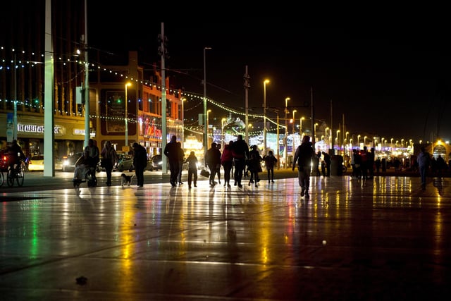 Members of the public admire the Illuminations as they walk along the promenade on a rainy October night