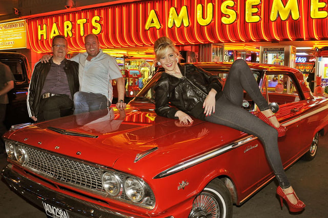 US cars and hot rods on the forecourt of Harts Amusements at Bispham. Russ Larcome (left) of UK Wheels Events and Charles Hart (Harts Amusements) with Russ's 1963 Ford Fairlane 500 and model Stacey Bradley from Cleveleys