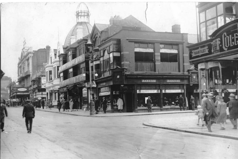 Church street junction of Coronation Street. The shop right of centre is Barkers and is advertising 'holiday wear' at the top of its windows. It was replaced in 1938 by Littlewoods. The white building is the Adelphi Hotel and to the right of the hotel is Taylors chemist