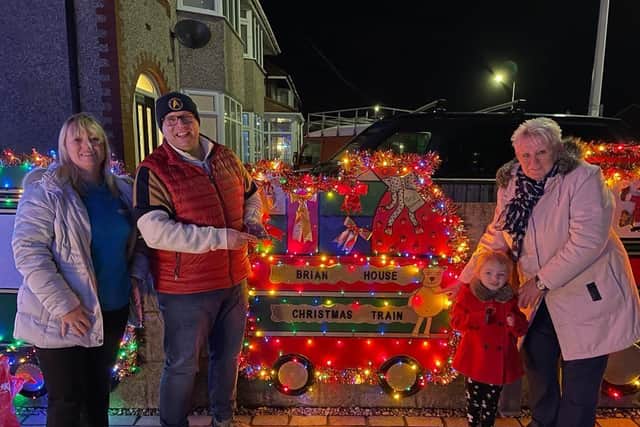 Paul Tilling with Michelle Lonican from Brian House Children’s Hospice and Elaine Tilling with a young fan at his Christmas lights display on Beach Road, Fleetwood,
last year