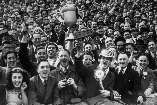 Football supporters at the FA Cup final between Manchester United and Blackpool at Wembley, London. One of the crowd holds aloft a replica of the cup.  United won the match 4-2