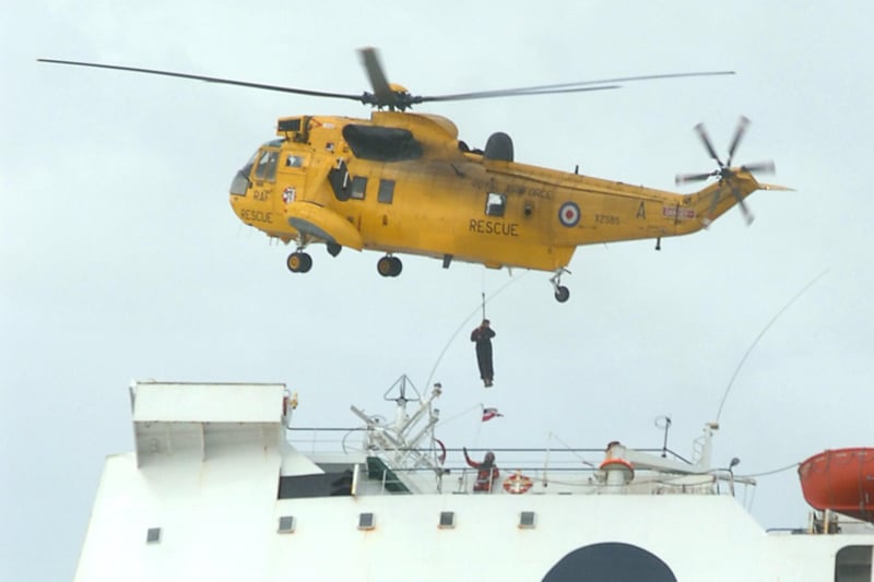 A sea rescue helicopter lowering salvage experts onto the stricken ferry at low tide