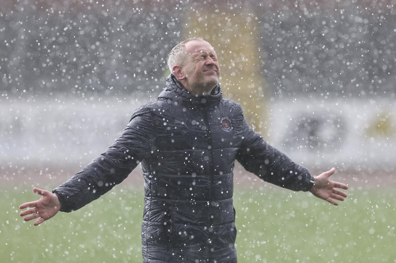 Neil Critchley celebrates with the fans during a hailstone storm at the end of the match.