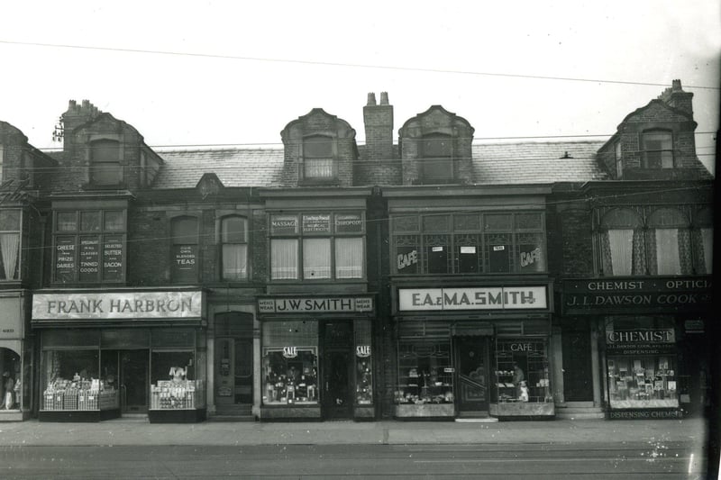 Lytham Road shops close to the Junction with Waterloo Road ( to the right ) . The Lido was further along on the left. According to the plaque this terrace of shops was built in 1892. Seen here in the 1950s the shops include from the left Greenhalgh's ladieswear ( only partly seen), Frank Harbron grocers, J.W. Smith  menswear, E.A. & M.A. Smith bakery and cafe and J.L.Dawson Cook dispensing chemist and opticians. The tram lines can be seen in the foreground, but this tram route was to close in 1961
