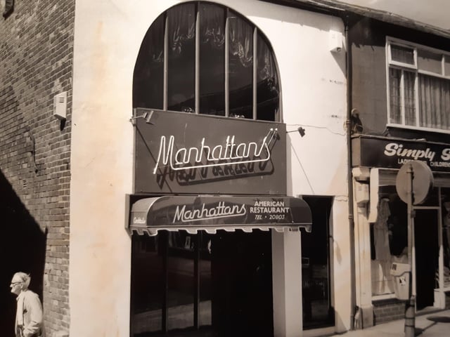 Manhattan's was an American style restaurant on Deansgate. In the caption on the back of the photo is says it sold cocktails in frosted glasses with a sugared rim and crushed ice made in an American blender...