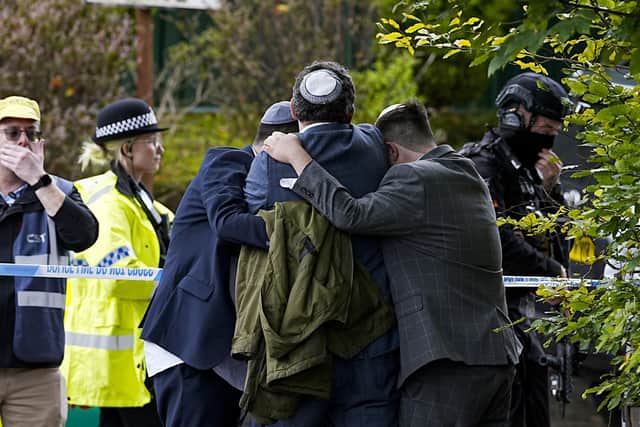 Members of the Jewish community comfort each other near to the Heaton Park Hebrew Congregation synagogue