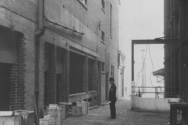 The police officer in this picture is looking at the spot where two bombs were found in a dustbin at the foot of Woolworth's building. The Tower is seen on the right and the street he is stood in, is long gone Heywood Street