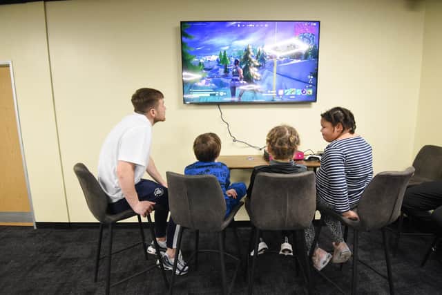 Jordan Thorniley plays a video game with some children