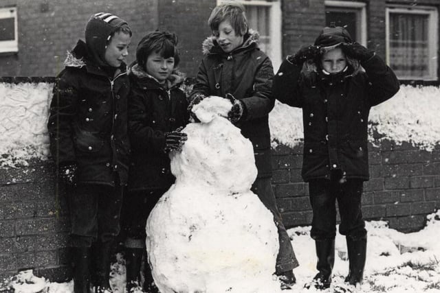 Four youngsters building snowman in Princess Street