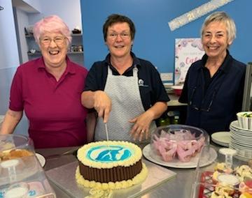 Visitors were able to tuck into a 21st birthday cake, being cut here by cook Phyllis Maguire, watched by volunteers Barbara Maguire (left)and Maureen Earl.