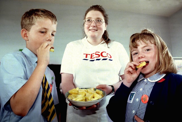 Health Awareness Week, 1998. Pic shows 10 year-olds Ryan Armitage (left) and Meggie Speakman from St Nicholas' School enjoying a slice of pineapple being offered by Tesco's Consumer Services Officer Angie Robinson, on the Tesco's Healthy Eating stand