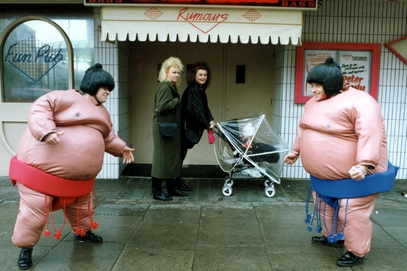 Inflatable Sumo wrestling outside Rumours, Blackpool.  Pictured are Paul Brook and Paul O'Shea watched by passers-by Jane and Julie Wetherby