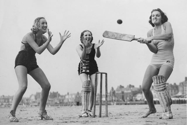 21st August 1937: Three girls enjoying a game of cricket on the beach at Blackpool