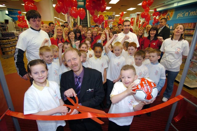 Re-opening of the Woolworths store in Bank Hey Street, 2006. Layton Junior Under 8 football team members Charlie Henderson (left) and Mason Tyler help store manager Brian Heeler to cut the ribbon, watched by members the team and Woolworth's staff