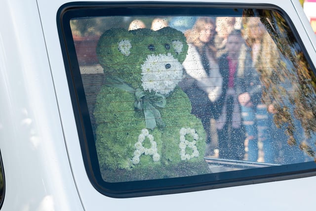 A green teddy sits in the back of the funeral cortege