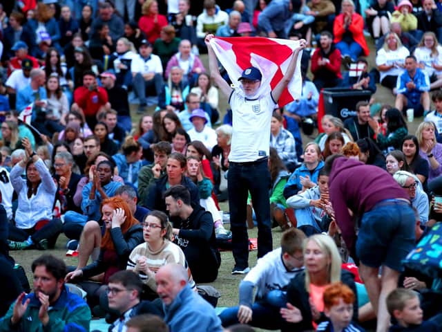 An England fan at Devonshire Green holds up a flag as they watch a screening of the UEFA Women's Euro 2022 semi-final match between England and Sweden held at Bramall Lane, Sheffield. Isaac Parkin/PA Wire.
