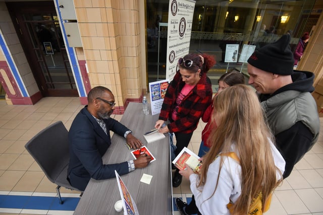 Sir Lenny Henry signs copies of his books for fans.