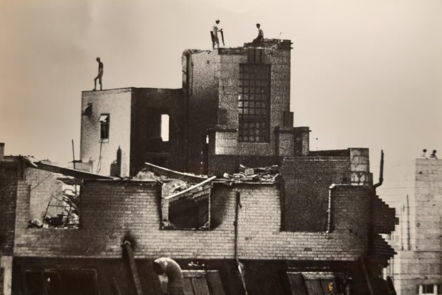 Workers high up on the edges of the fire-ravaged walls as demolition work begins