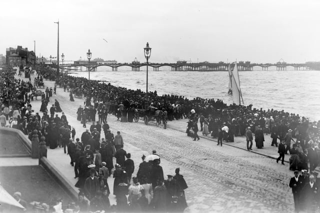 Crowds on Central Promenade, Blackpool in the late 1890s. In the distance on the far left is the old Manchester Hotel, demolition of this building began on 31st of October 1935 and the new Art Deco style hotel opened, for the start of the 1936 season, on 30th May. The Victoria Pier in the far distance opened in 1893 and was renamed South Pier in 1930. Central pier opened in 1868