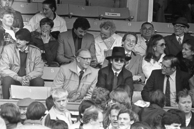 Elton John sat in the Blackpool directors stand during the Keith Mercer testimonial match between Blackpool and Watford. On his right is former Arsenal boss Bertie Mee