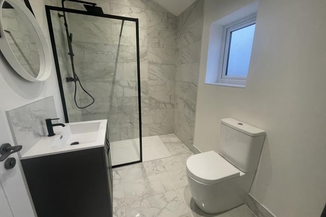 The shower room oozes style. It is fitted with a contemporary suite, comprising walk-in shower enclosure, wash hand basin set in a vanity-style unit, low-flush WC and ladder-style radiator. The floors and walls are tiled.