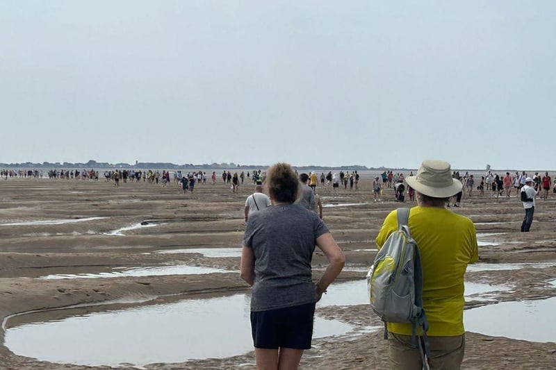 Walkers make their way across sands normally covered by the sea