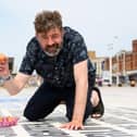 Reporter Richard Hunt prepares to crack an egg on the Comedy Carpet in Blackpool to see if it will fry. Photo: Kelvin Stuttard