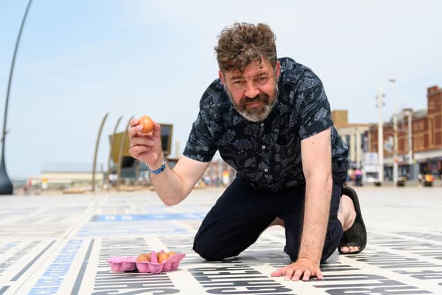 Reporter Richard Hunt prepares to crack an egg on the Comedy Carpet in Blackpool to see if it will fry. Photo: Kelvin Stuttard