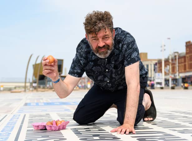 Reporter Richard Hunt prepares to crack an egg on the Comedy Carpet in Blackpool to see if it will fry. Photo: Kelvin Stuttard